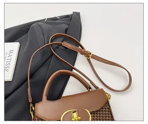 Detail showing the adjustable thin strap with gold buckle on a brown houndstooth bag