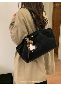 Detail of black matte tote bag with leopard heart mirror and plush ball charms