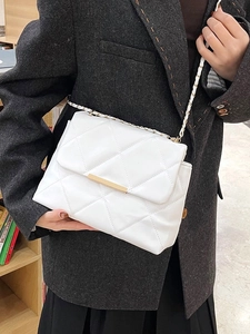 White quilted crossbody bag with gold chain strap shown on a dark blazer outfit