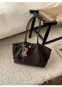 Deep brown leather tote bag with heart charm and leopard ribbon on plush rug