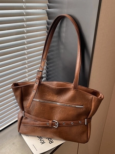 Retro brown leather tote bag with stylish metal zipper and belt buckle detail in natural light
