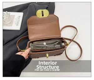 Detail view of the brown woven crossbody bag interior with zipper and main compartments