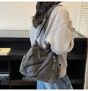 Model wearing dark grey denim hobo bag with multiple diagonal zippers for daily commute