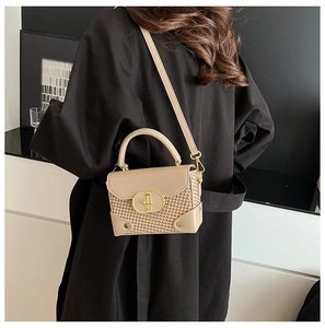 Detail of beige woven crossbody bag featuring a golden oval metal lock and smooth leather trim