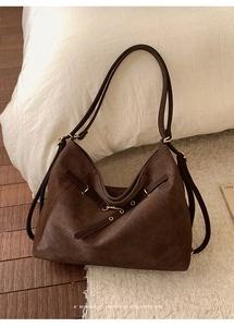 Detail of a large vintage brown woven tote bag with metallic buckle and leather straps