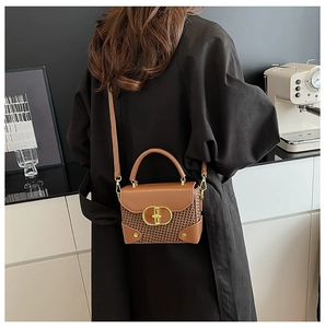 Close-up of brown textured leather bag with woven panels and golden metallic buckle