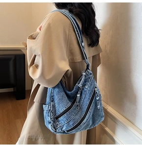 Detail of blue denim hobo bag showing retro distressed texture and metal zip pockets