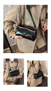 Close-up of black glossy leather handbag with magnetic buckle and dual shoulder straps