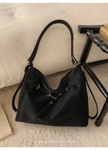 Close-up of black woven leather Hobo bag with gold buckle in a retro minimalist style
