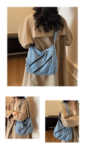 Detail of blue washed denim shoulder bag with industrial style diagonal zippers
