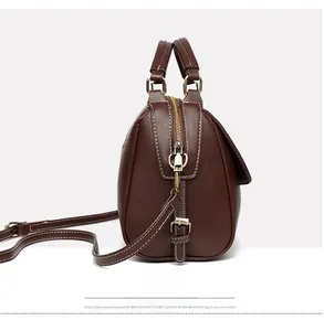 Side view of dark brown pebbled leather tote with golden zippers and white stitching