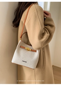 Detail of Pantor bucket bag featuring cream fabric, brown leather trim, and gold clasp