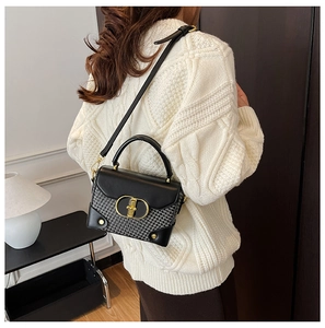 Detail of vintage crossbody bag with gold clasp and houndstooth texture on white sweater