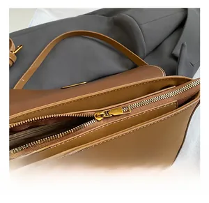 Details des goldenen Reißverschlusses und weißer Nähte an brauner Lederhandtasche