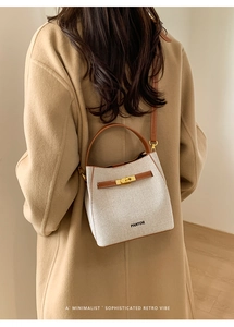 Rear view of a model wearing the canvas and leather bucket bag with brown shoulder strap