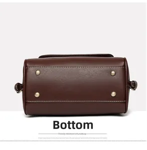 Detail view of brown leather bag bottom with golden metal feet and neat stitching