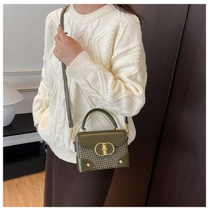 Detail of vintage green woven crossbody bag with gold buckle on a knit sweater outfit