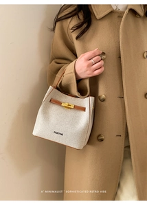 Detail of canvas bucket bag with brown leather trim and metallic buckle closure