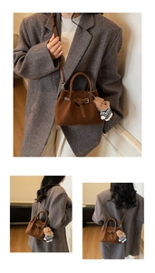 Detail of dark brown suede bucket bag with metal buckle and cute bear charm accessory