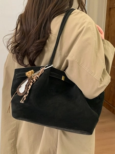 Large black suede tote bag with leopard charm worn with a beige trench coat
