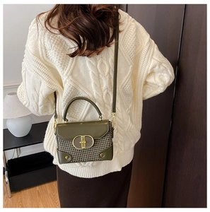Detail of green woven small square bag featuring a vintage gold oval twist lock buckle