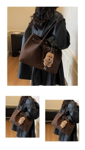 Detail view of large dark brown woven tote bag featuring a cute plush bear charm
