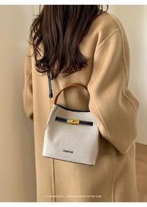 Detail of canvas and leather bucket bag with brand logo shown on woman in wool coat