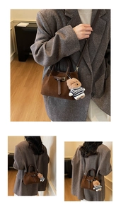 Detailed view of brown suede bucket bag with retro metal buckle and teddy bear charm
