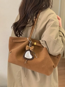 Brown suede tote bag with leopard heart charm and bow, shown on model for daily use