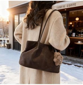 Detail of a large dark brown suede tote bag with a cute plush bear charm in winter