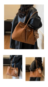 Detail of brown woven texture tote bag featuring a plush bear charm and metallic buckle