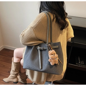 Detail of grey woven tote bag featuring a cute plush bear pendant and textured PU finish