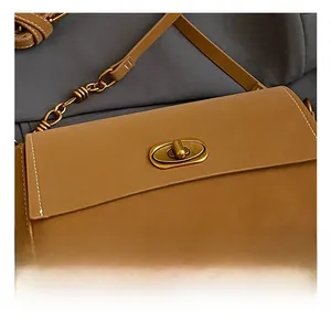 Detail einer braunen Umhängetasche aus Leder mit goldenem Drehverschluss und Narbung
