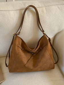 Vintage large brown matte tote bag with woven side panels and buckle on a beige sofa