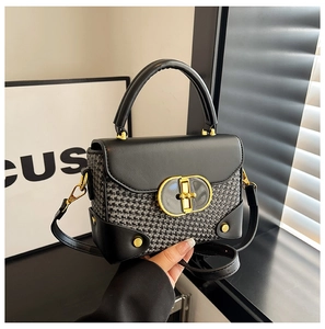 Detailed view of bicolor tweed handbag with golden oval twist lock and leather handle