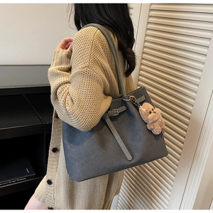 Detail of grey tote bag with woven texture and a cute brown plush bear charm