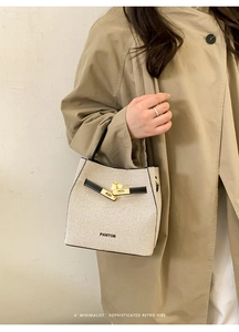 Detail of the woven canvas bucket bag featuring black leather trim and gold metal hardware