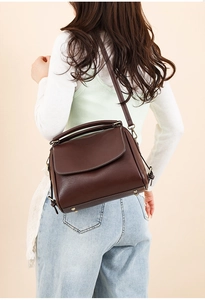 Detail view of vintage dark brown leather handbag with metal studs and top handle