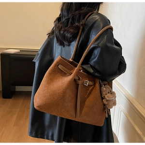Detail of vintage brown woven tote bag featuring a textured finish and plush bear charm