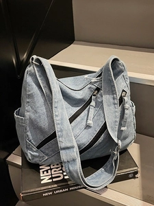 Stylish denim shoulder bag in light blue wash with front zipper pocket and adjustable strap