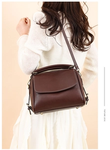 Detailed view of dark brown retro leather handbag with contrast stitching and metal feet