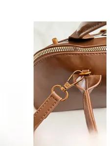 Close-up of premium dark brown leather texture with golden hardware on a shell bag