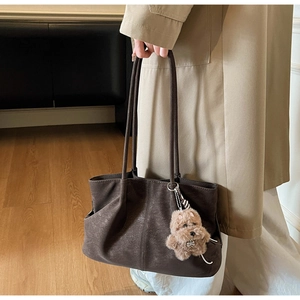 Detail view of brown tote bag with vintage texture, soft folds and plush puppy charm