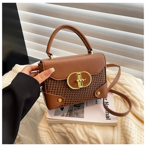 Detail of vintage woven leather handbag with gold oval twist lock and rivet reinforcement