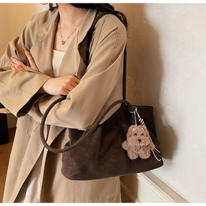Detail of a large dark brown faux suede tote bag with a plush puppy keychain accessory