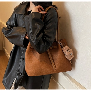 Detail of vintage brown woven tote bag with adjustable strap and plush bear accessory