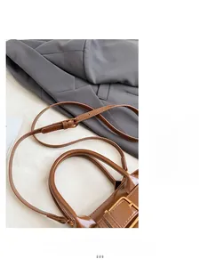 Detail of adjustable slim brown leather shoulder strap with gold metal buckle