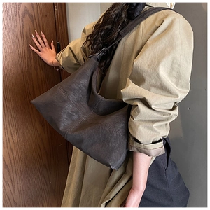 Detail view of large brown hobo bag with cross stitching on soft matte leather texture