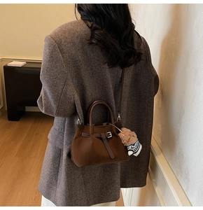 Detail of dark brown suede bucket bag with leather strap and cute bear plush charm