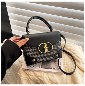 Close-up of retro houndstooth pattern bag with CD-style gold metal clasp and leather strap